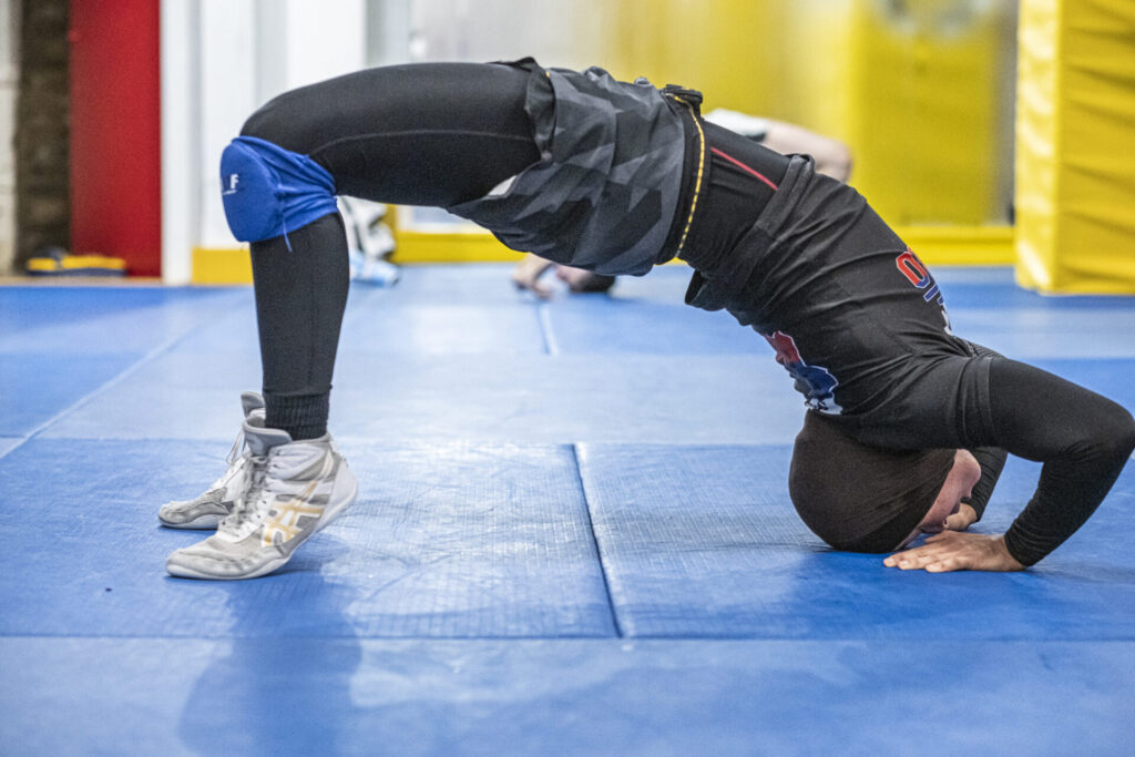Martial artist holding a bridge position during flexibility drills at London Fight Factory.